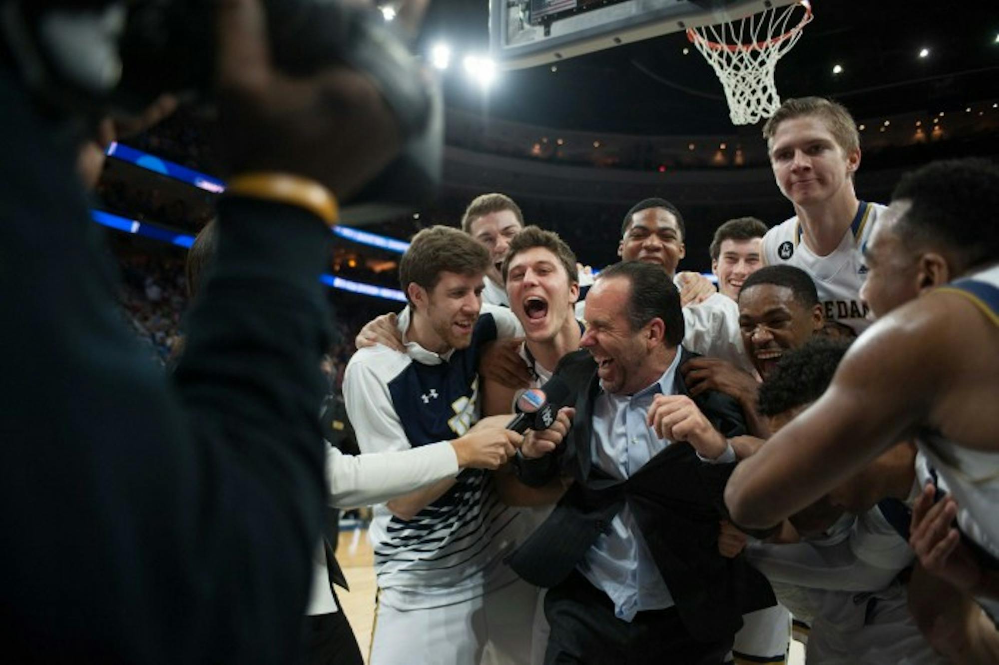 Irish players celebrate with head coach Mike Brey following Notre Dame’s 61-56 win over Wisconsin on Friday night in Philadelphia.