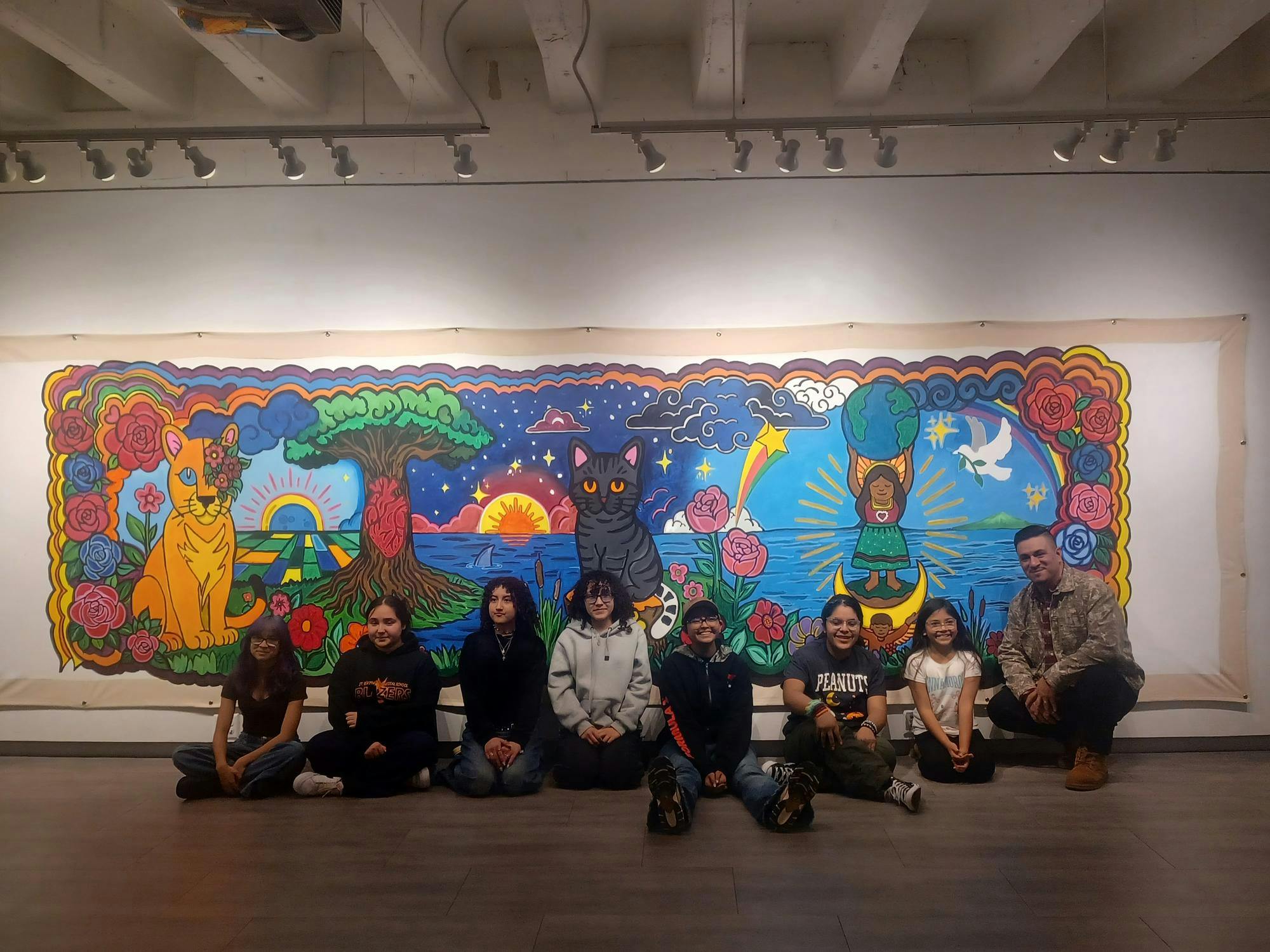 Student artists pose with local artist Freddy Rodriguez with artwork