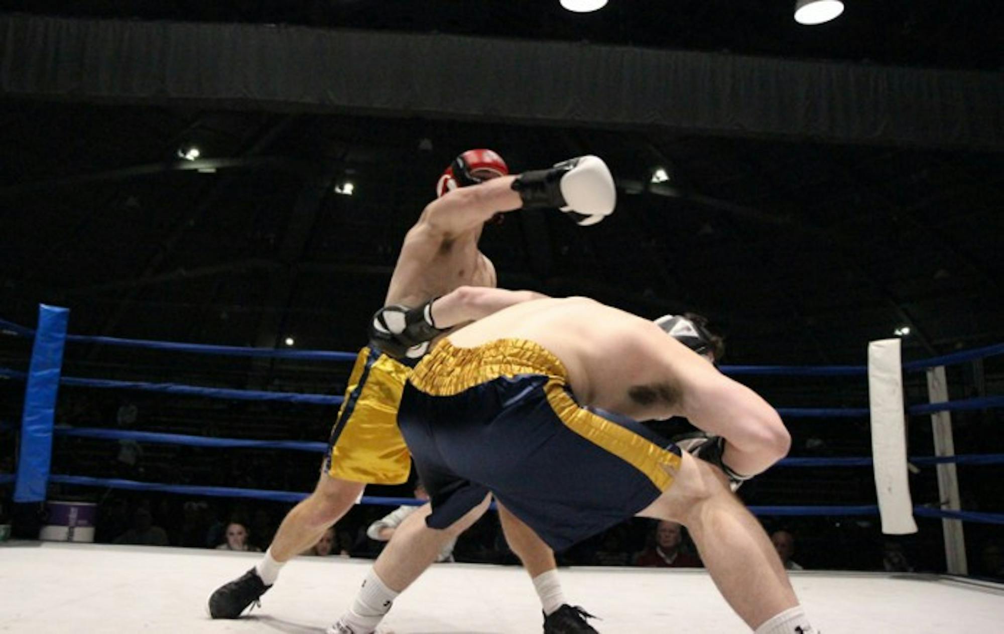 Senior captain Ricky Neville, right, prepares for a hook from senior Michael Smoljan in the semifinal round Tuesday night. Neville was victorious by split decision and will fight junior Evan Escobedo in the finals Sunday for a chance at his first championship after falling in last year's title bout.