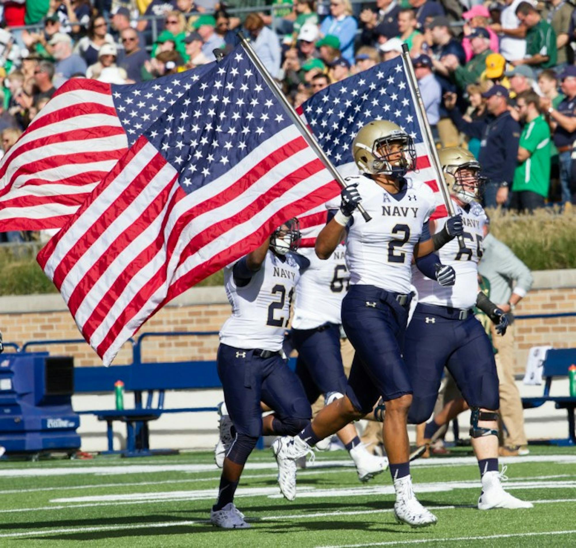 Navy players take the field carrying American flags before the game Saturday at Notre Dame Stadium.
