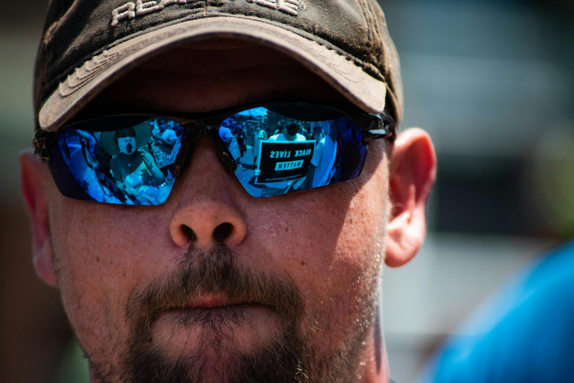 Counter-protesters reflected in the sunglasses of a Defend the Police rally protester.