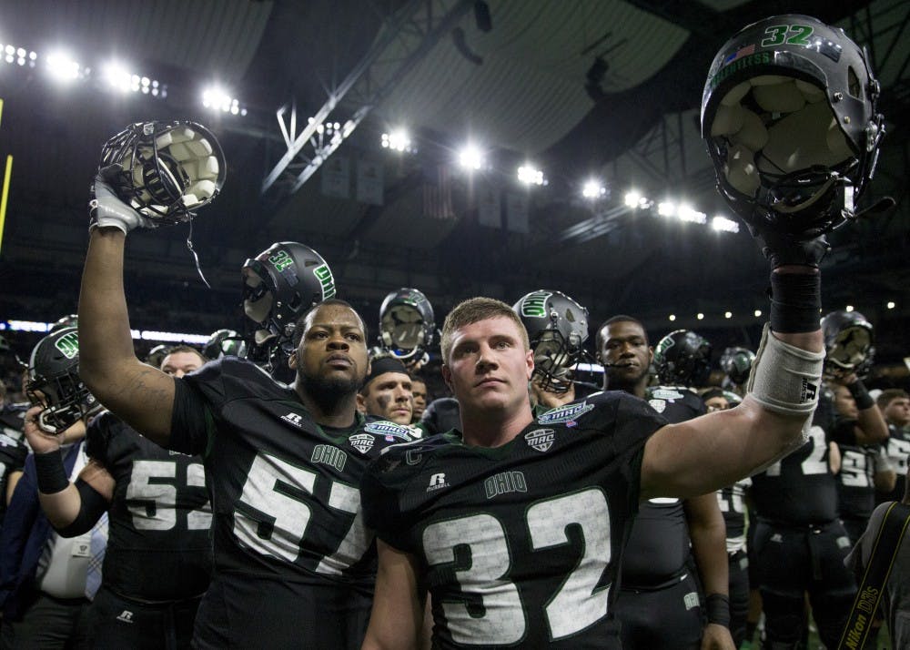 Ohio redshirt junior offensive lineman Durrell Wood (#57) and redshirt junior linebacker Quentin Poling (#32) raise their helmets during Alma Mater Ohio after Western Michigan beat the Bobcats 29-23 in the Marathon MAC Championship game at Ford Field in Detroit, Michigan. Ohio tested the #17 ranked team in the country, but a late interception sealed the game for WMU.