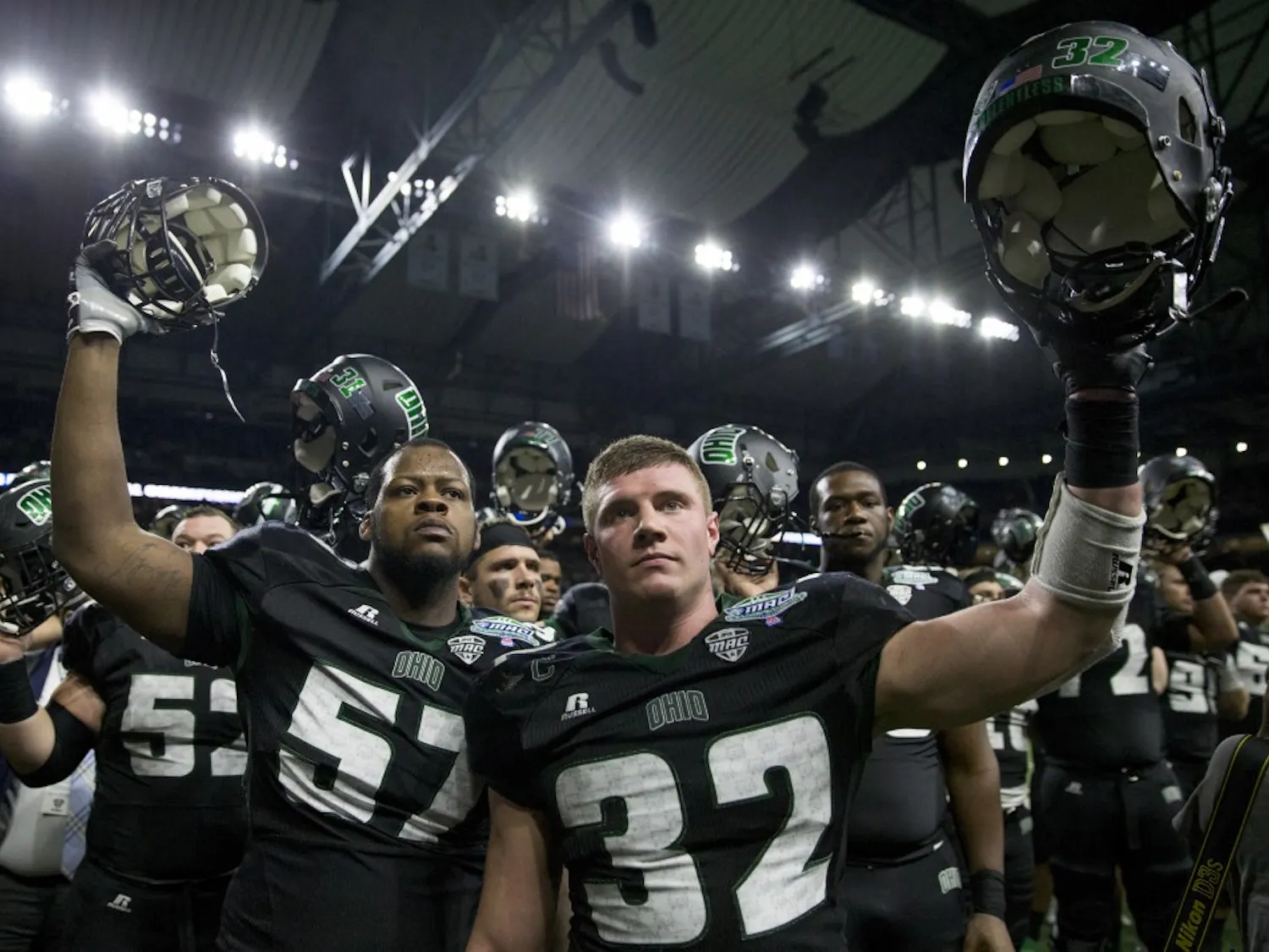 Ohio redshirt junior offensive lineman Durrell Wood (#57) and redshirt junior linebacker Quentin Poling (#32) raise their helmets during Alma Mater Ohio after Western Michigan beat the Bobcats 29-23 in the Marathon MAC Championship game at Ford Field in Detroit, Michigan. Ohio tested the #17 ranked team in the country, but a late interception sealed the game for WMU.