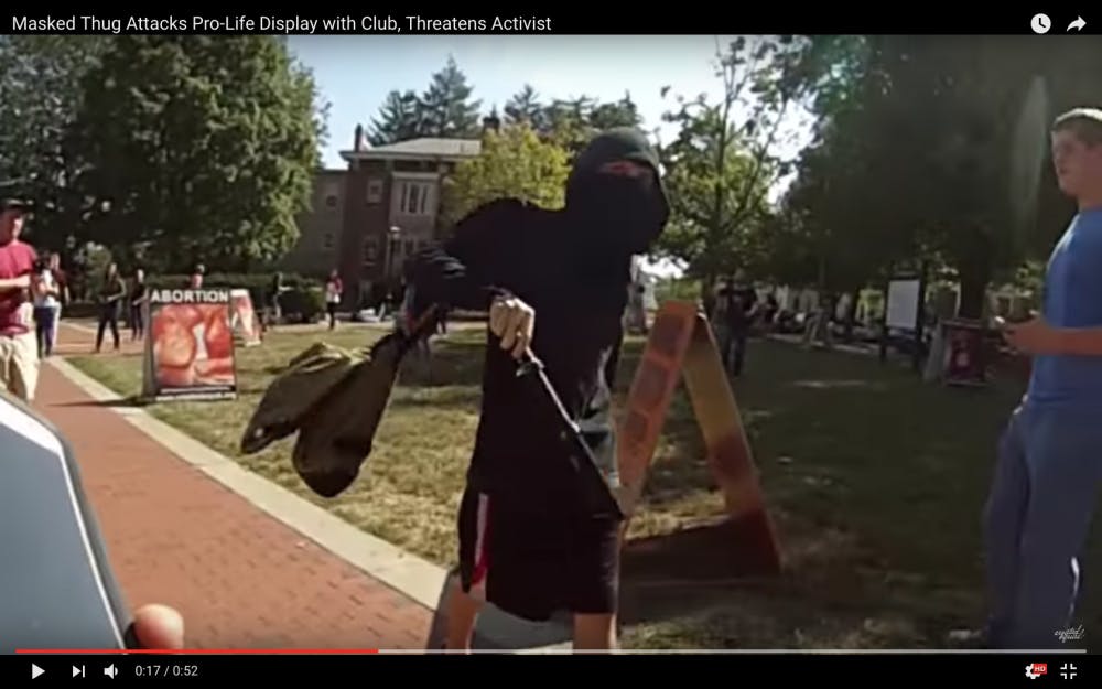 A masked man struck anti-abortion signs at a protest on&nbsp;Friday.