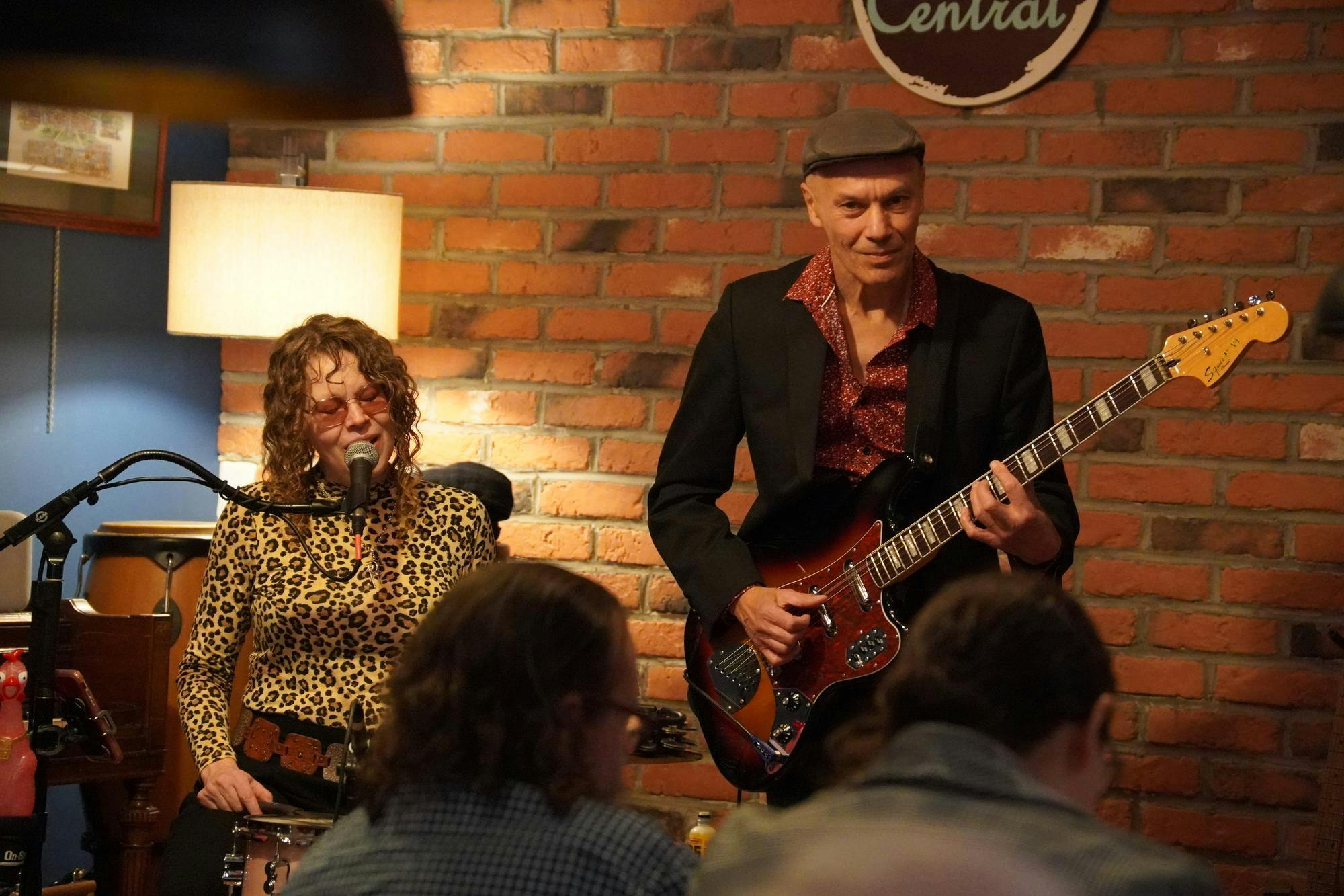 Woman sitting and singing on the left and a man playing the guitar on the right.