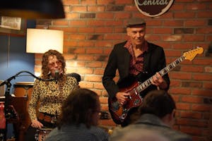 Woman sitting and singing on the left and a man playing the guitar on the right.