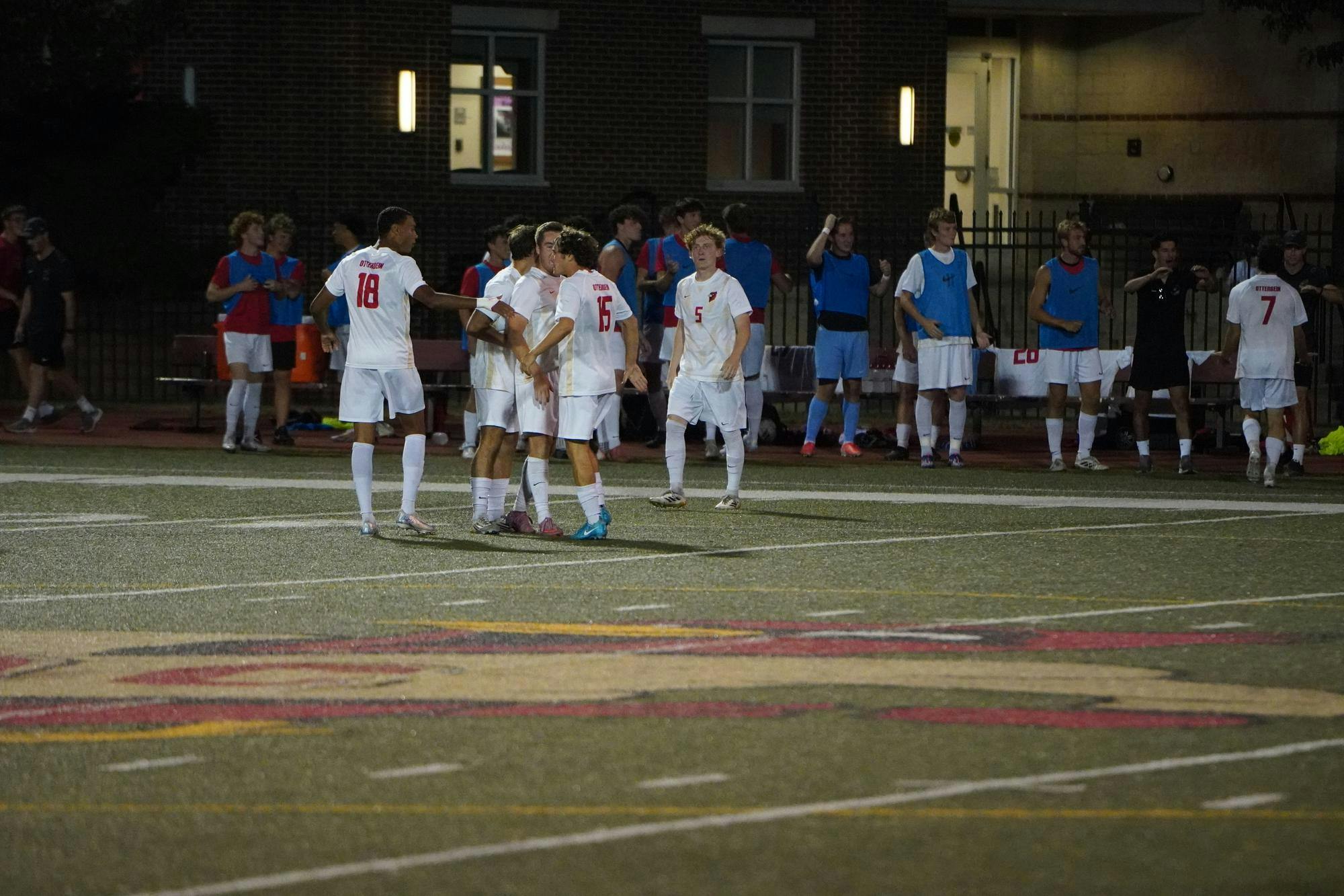 5 soccer players are standing on the field and 17 more are on the sidelines