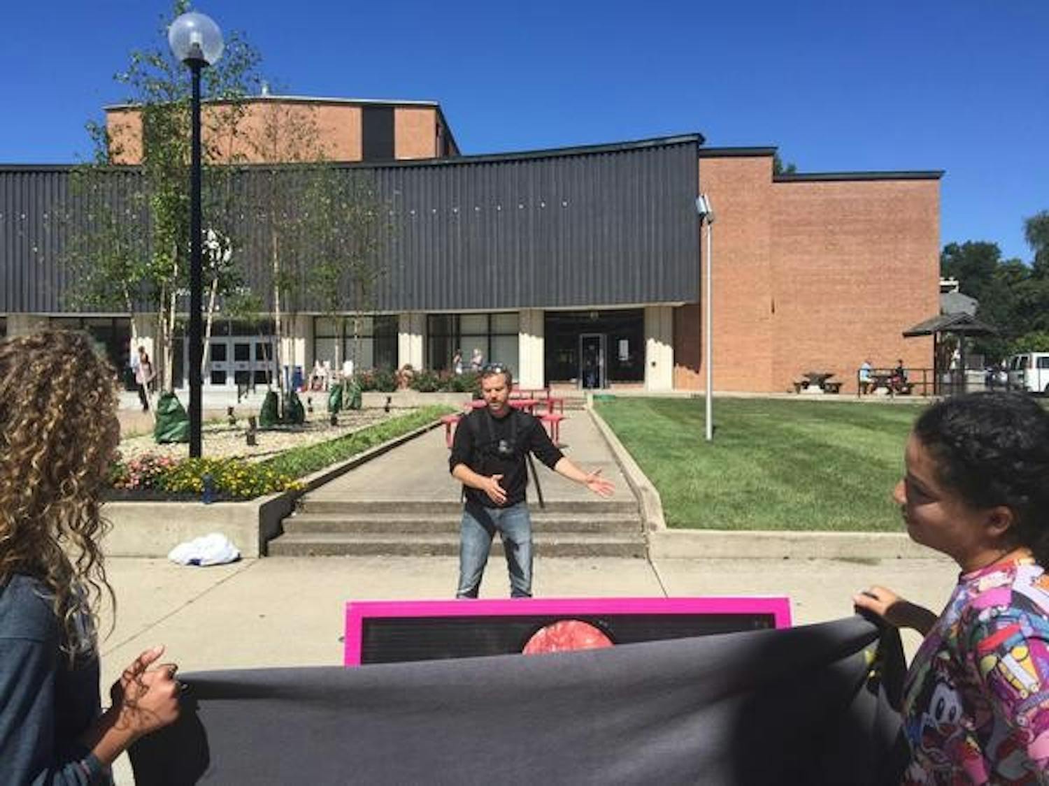 Created Equal organizer explains his stance as student protesters listen while covering a sign which displayed graphic images with a bed sheet.