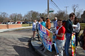 Students holding a comedic flag to cover an anti-abortion sign