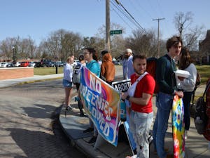 Students holding a comedic flag to cover an anti-abortion sign