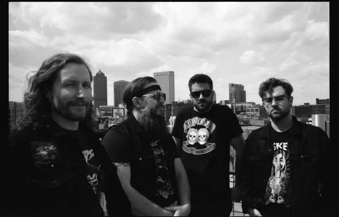 All four members of Denim Cobra band, posing in front of the Columbus Skyline for a group photo.