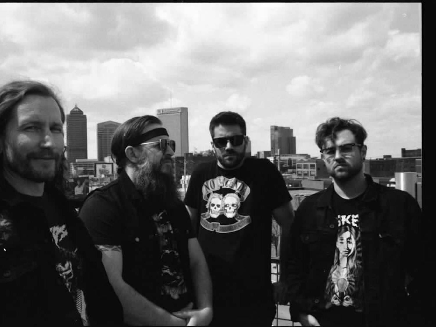 All four members of Denim Cobra band, posing in front of the Columbus Skyline for a group photo.