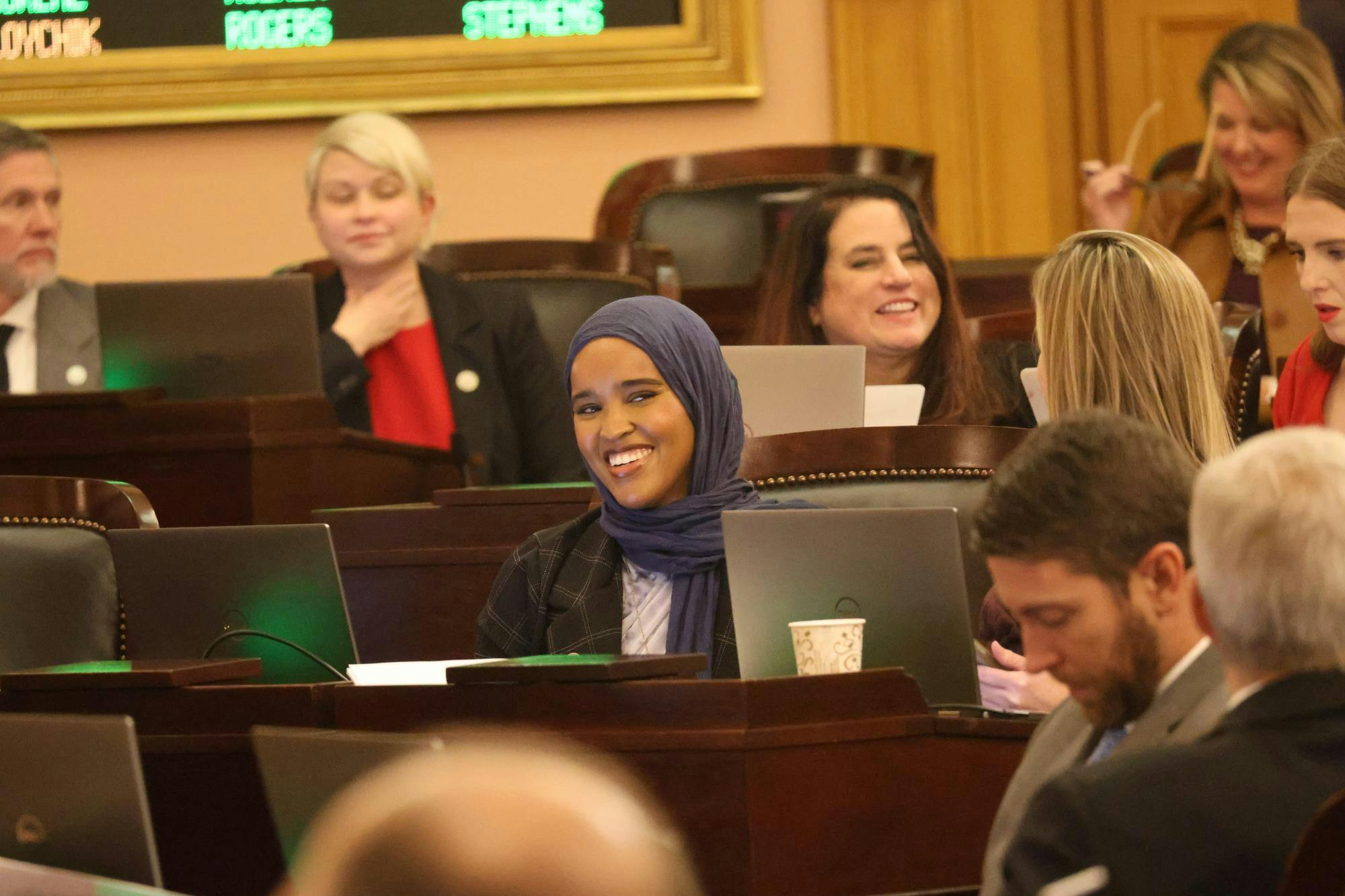 A women sitting and smiling at a meeting.