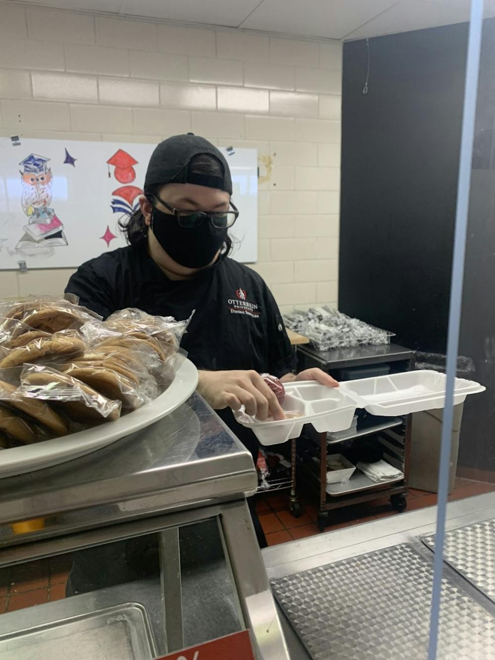 Otterbein Dining staff member Alex Trimble serves lunch to students in take-out containers to comply with COVID-19 guidelines.