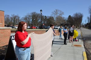 Isabel Elliott and Kaylie West hold a blanket to cover an anti-abortion sign