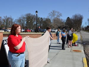 Isabel Elliott and Kaylie West hold a blanket to cover an anti-abortion sign