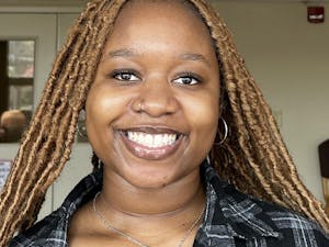 A young woman with long braided hair smiles for a picture.