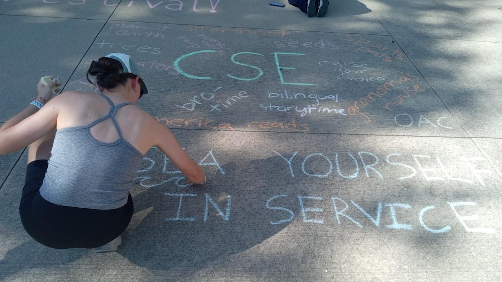 <p>A CSE worker chalking in front of the Courtright Library</p>