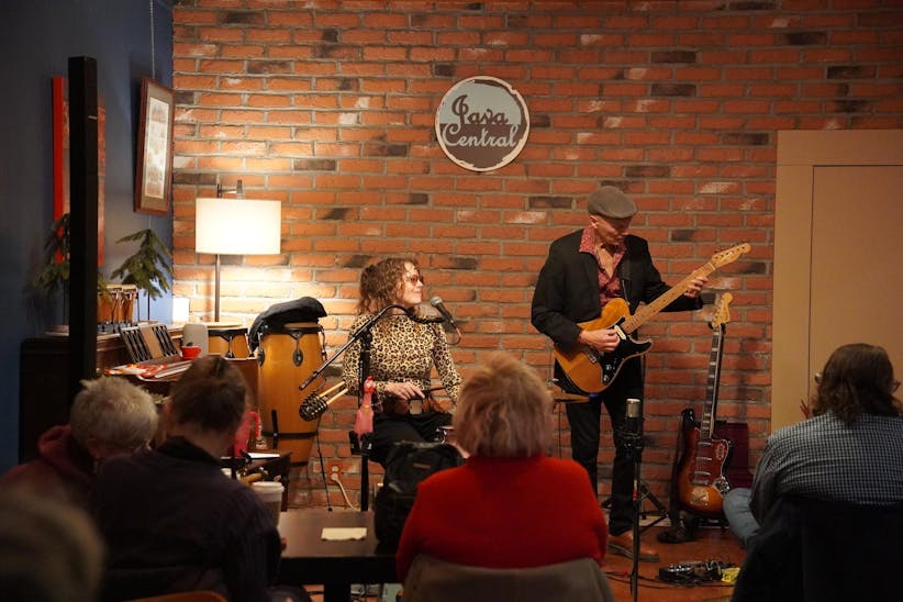 Woman sitting and singing on the left and a man playing the guitar on the right.