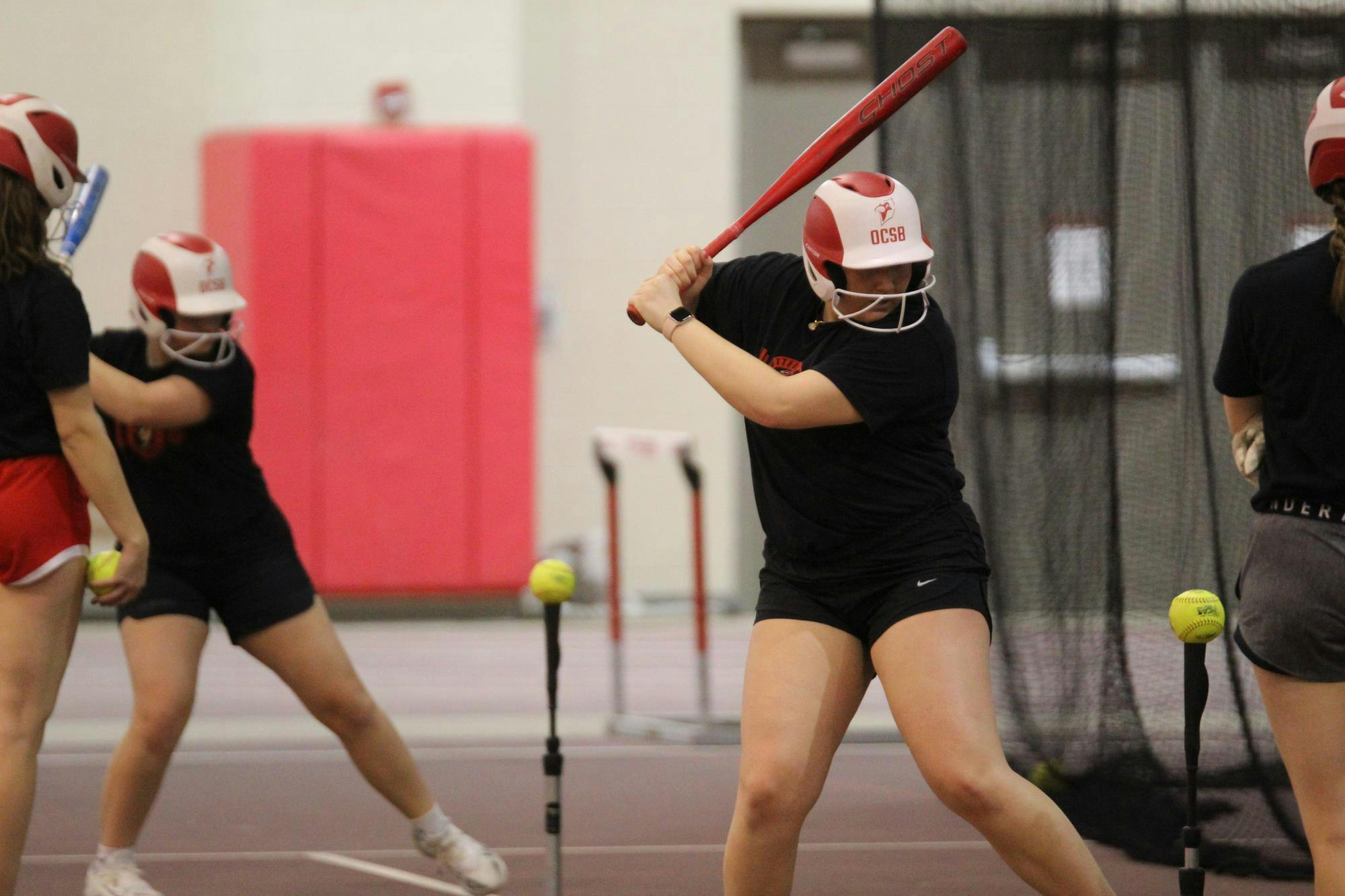 Otterbein softball players taking practice swings off tees before the upcoming season begins.
