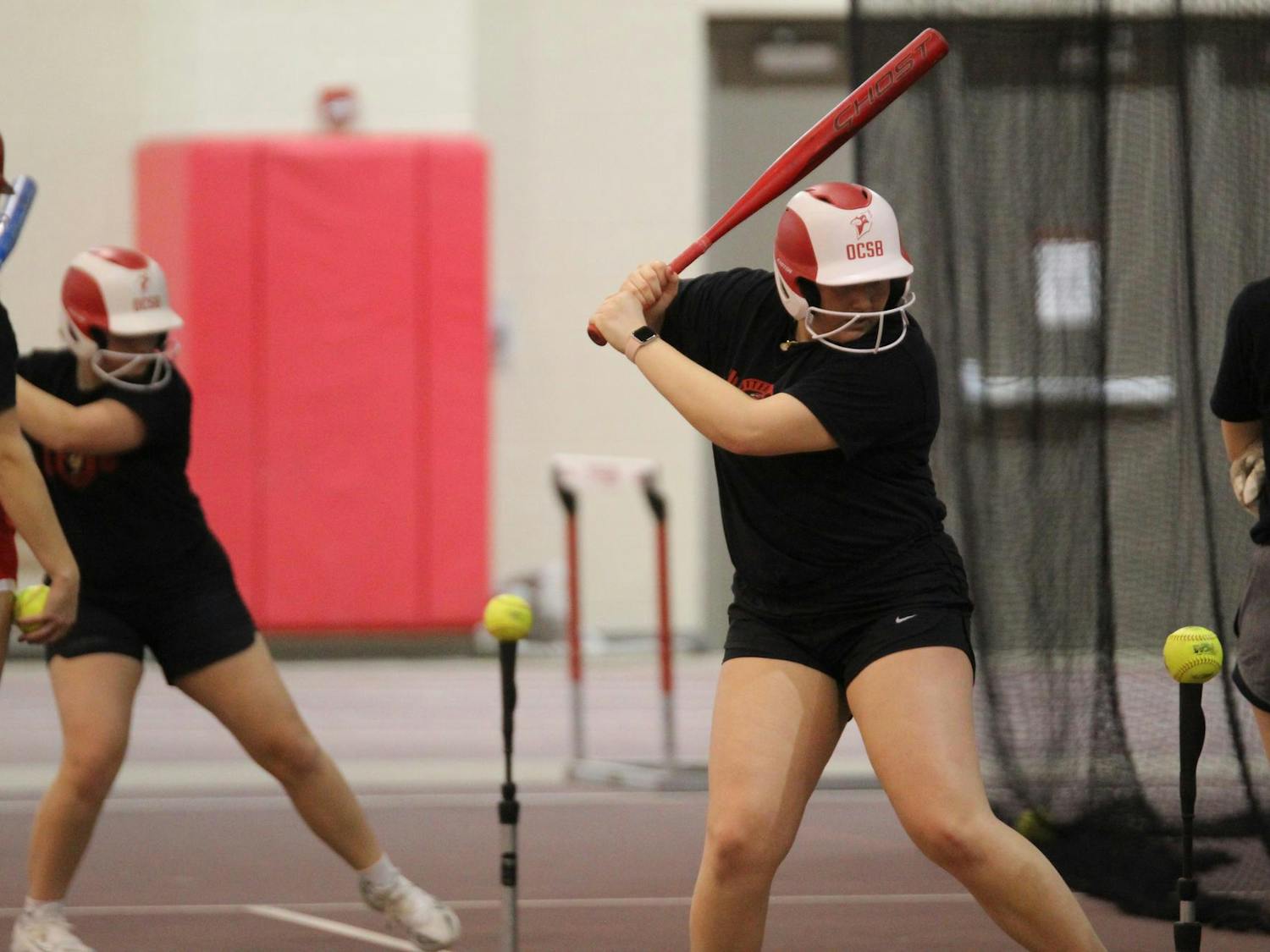Otterbein softball players taking practice swings off tees before the upcoming season begins.