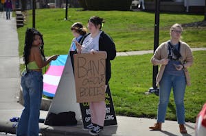 Students cover an anti-abortion sign while a member of Created Equal stands to the side