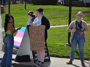 Students cover an anti-abortion sign while a member of Created Equal stands to the side