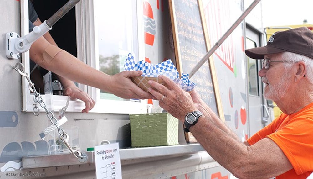	<p>A customer at the Challah Food Truck is handed his purchase.</p>