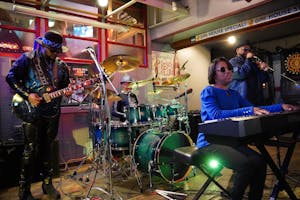 A band with a guitar player, drummer, keyboard player, and lead singer playing in a small bar area