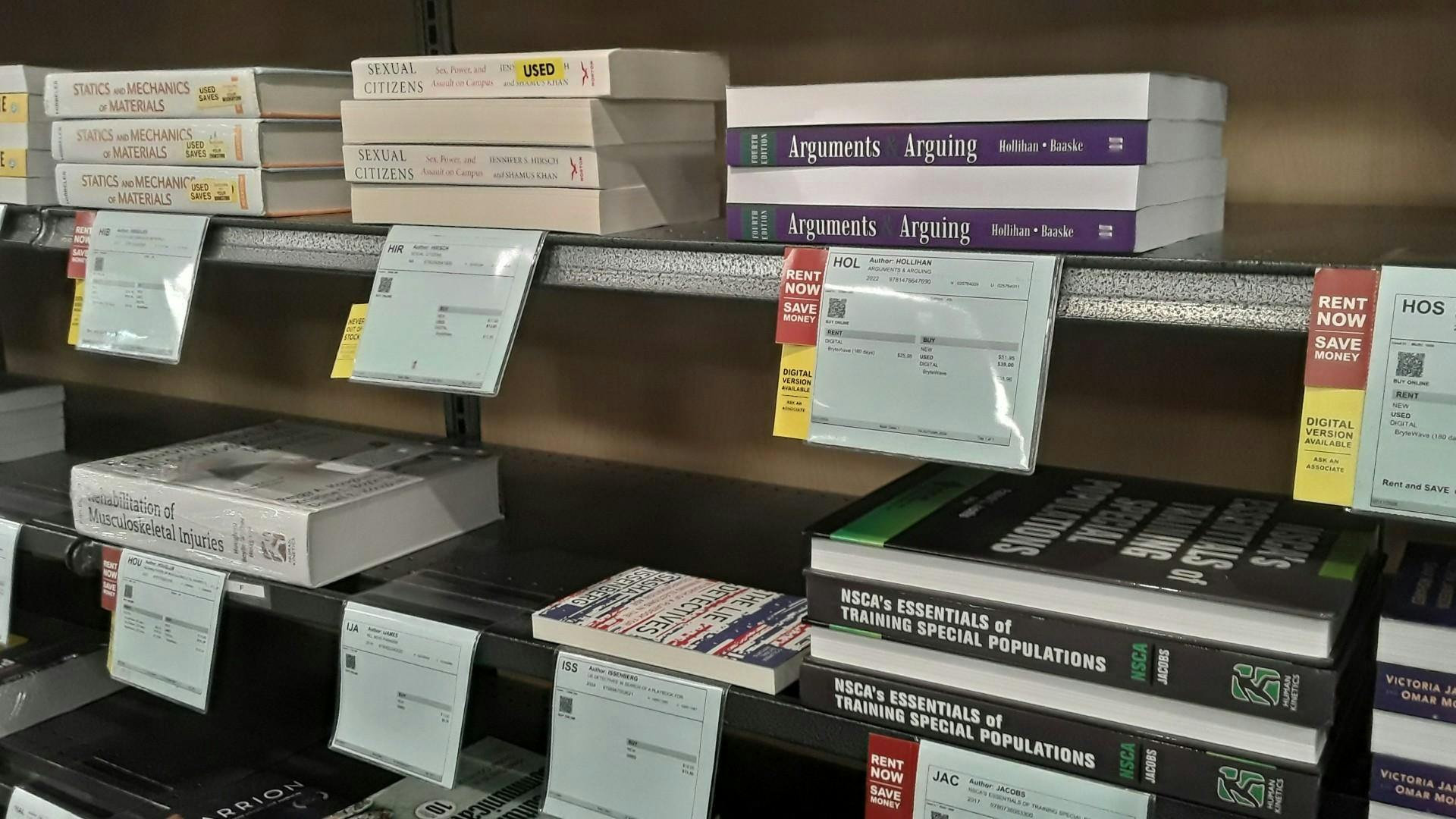 Several textbooks stacked horizontally on a bookstore shelf.