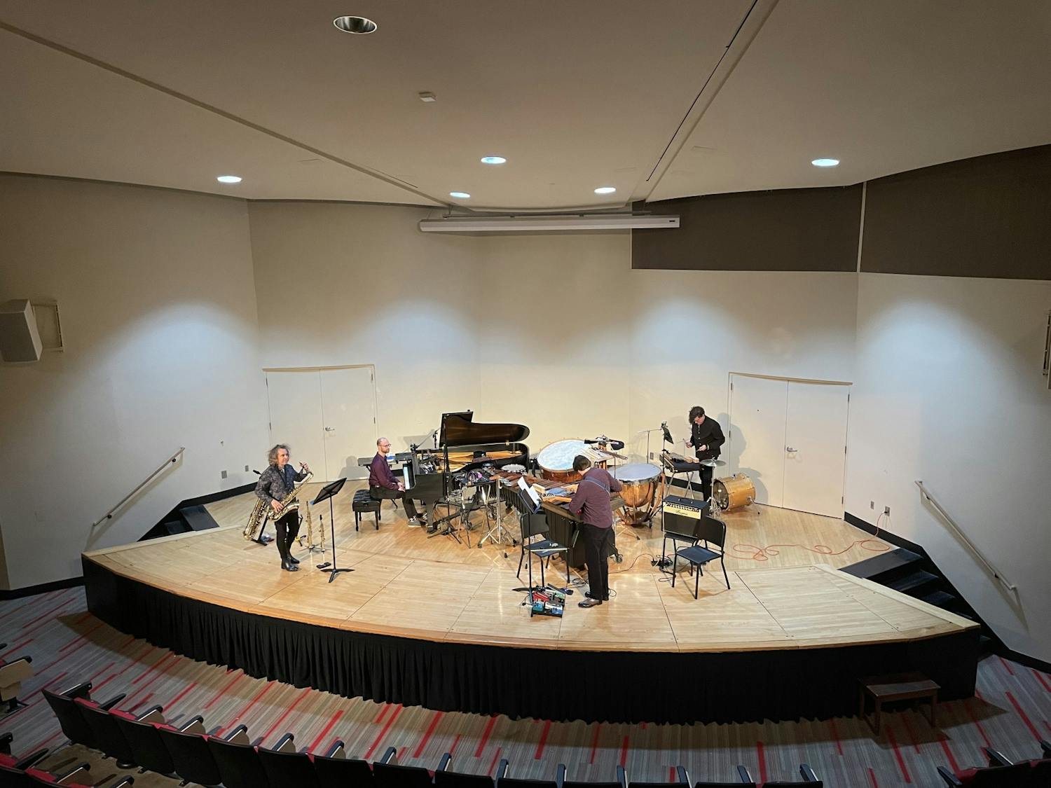 The four members of The Hinge Ensemble play the piano, saxophone, percussion, and electric guitar.