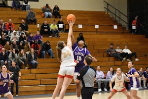 Otterbein and Capital women's basketball players jump midair to grab the ball.