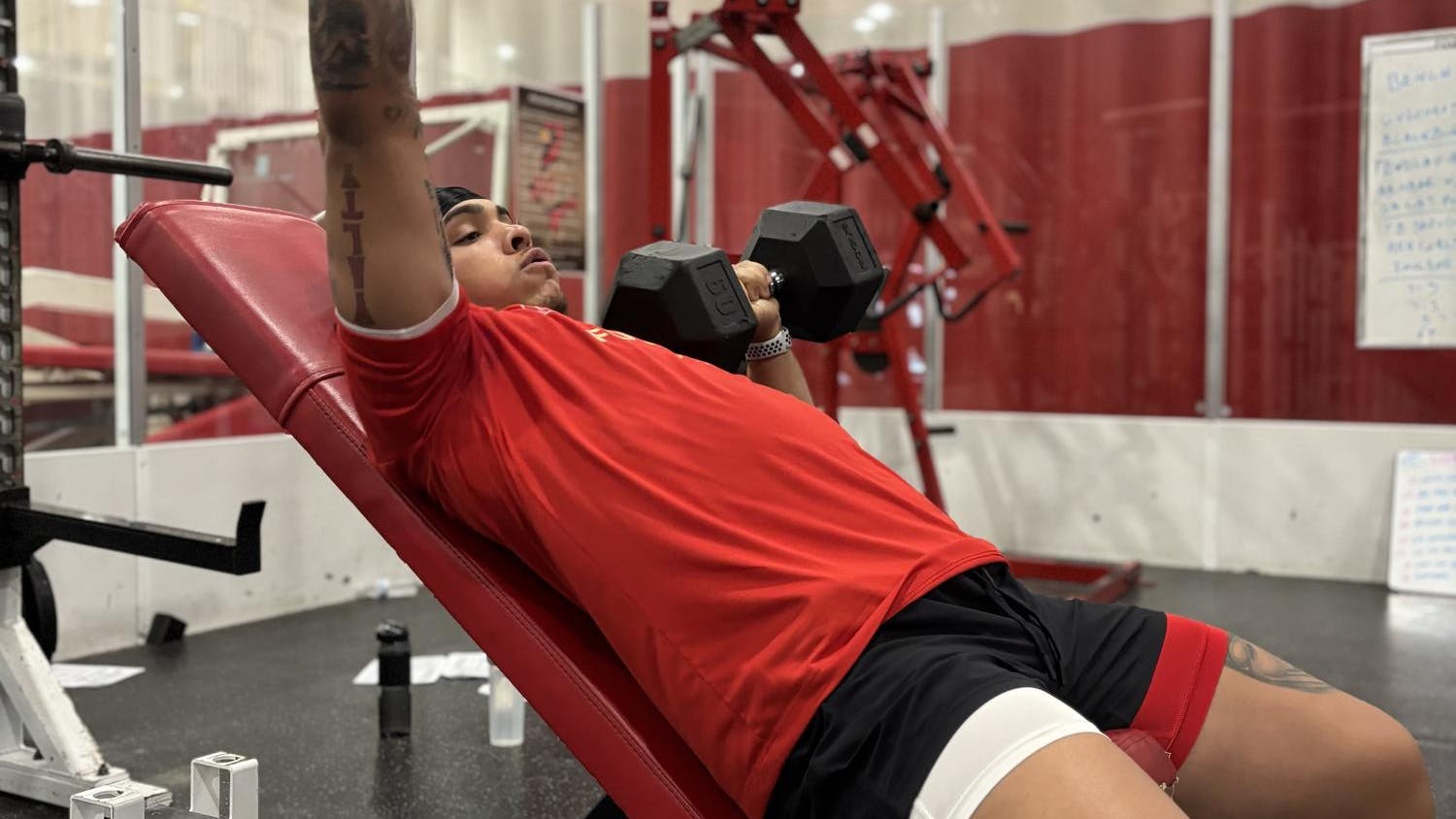 Football athlete incline dumbbell bench pressing in the weight room