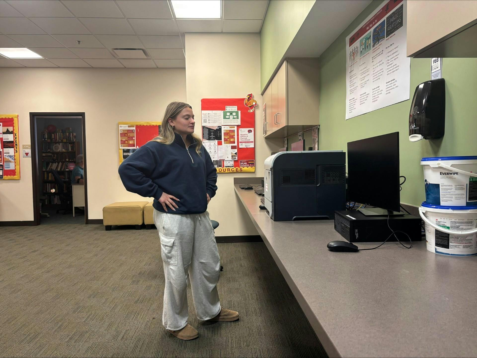 A woman with her hands on her hips stares at a printer