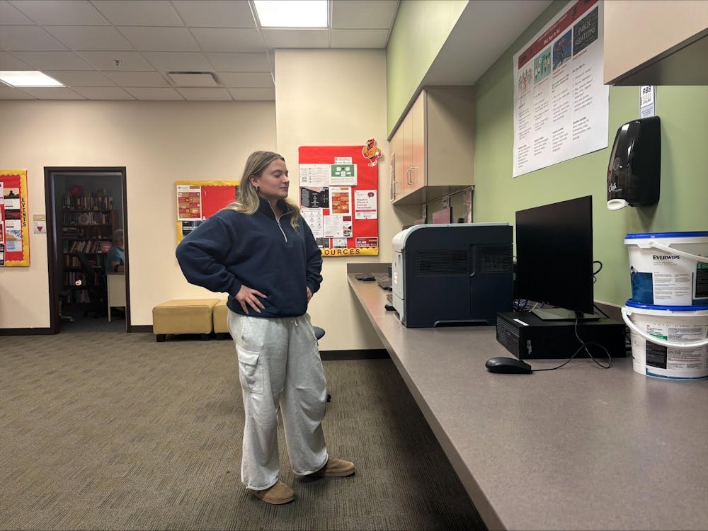 <p>A staged photo of a student looking at one of the many broken printers in the Art and Communication building.</p>