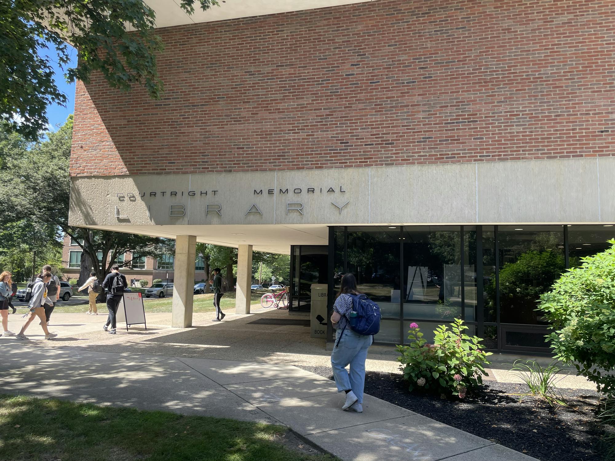Students walk to and from the library entrance.