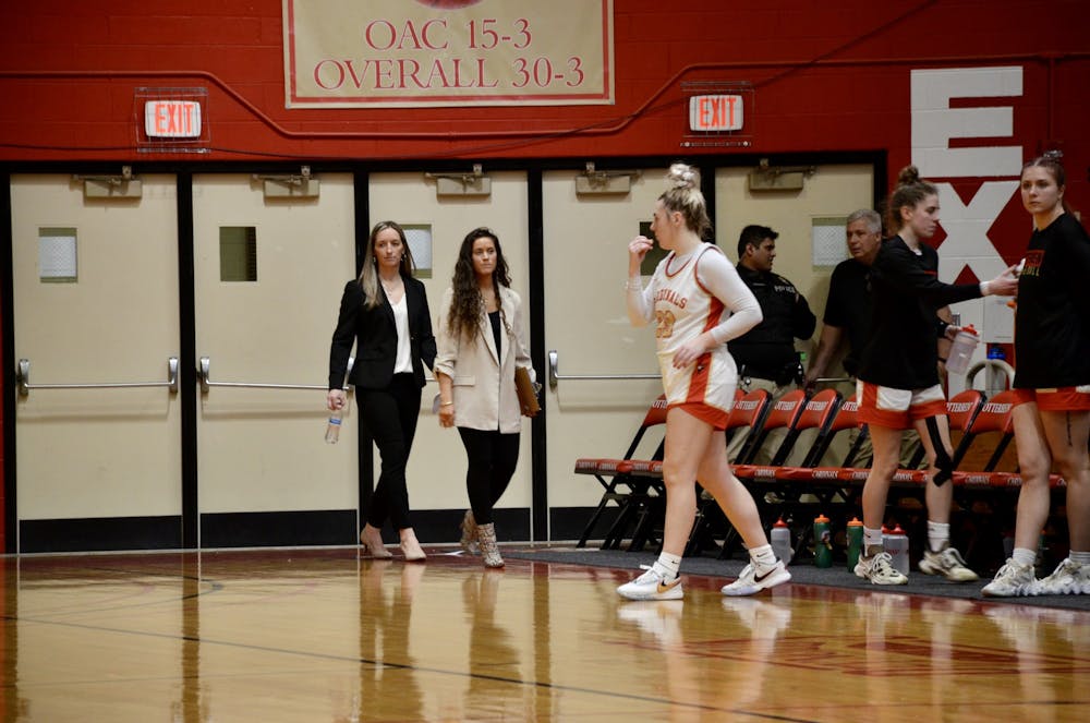 <p>Head coach Diana Noles (left) and assistant coach Delaney Cutteridge (right) walk onto the Otterbein University basketball court while players prepare for a game.&nbsp;</p>