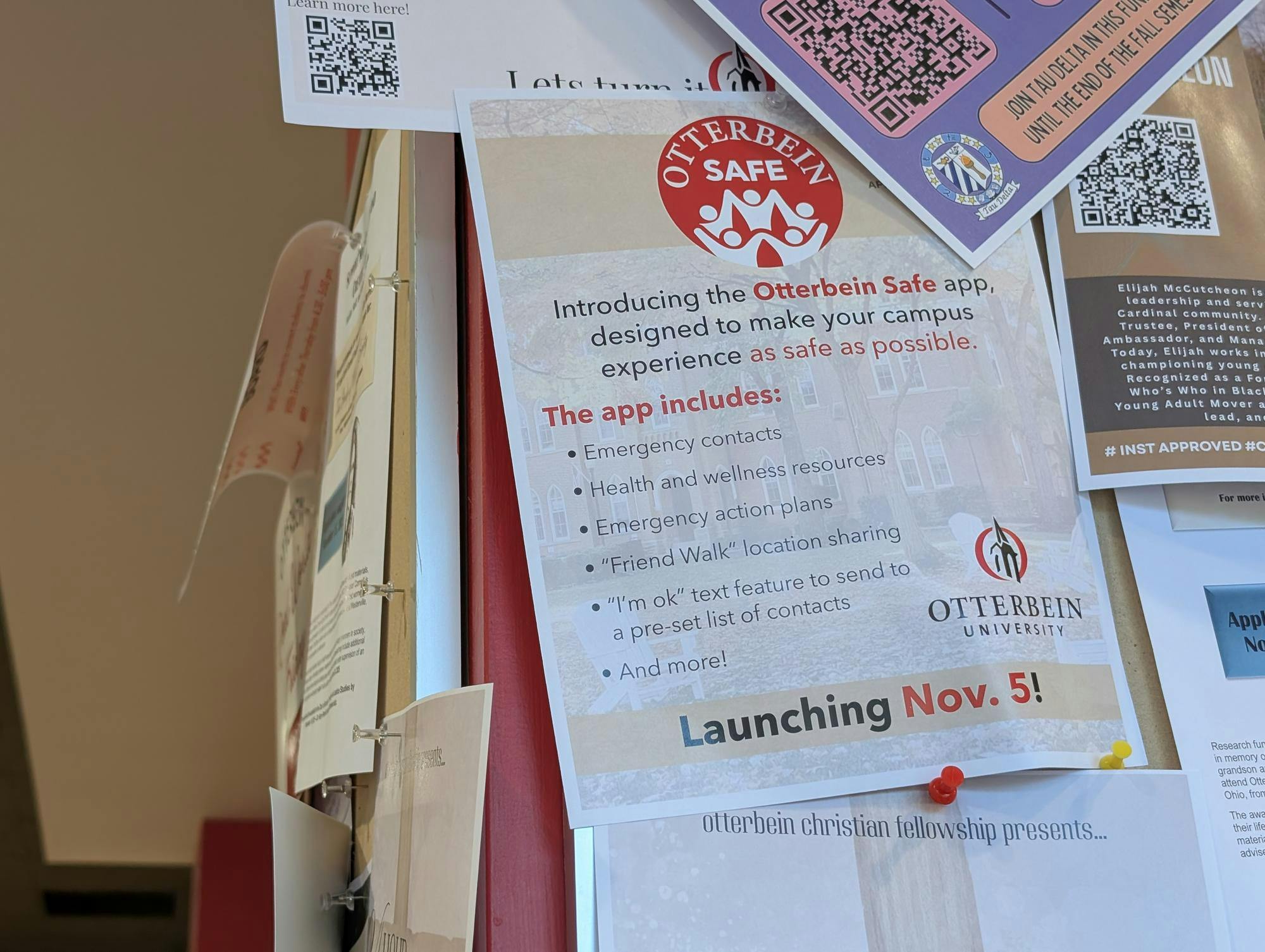 A flyer promoting the Otterbein SAFE app is pinned to a bulletin board with many other flyers around it.