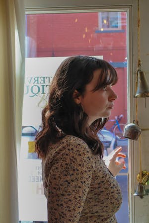 Girl with brown hair looking to the right side at hanging brown bells inside of a building.