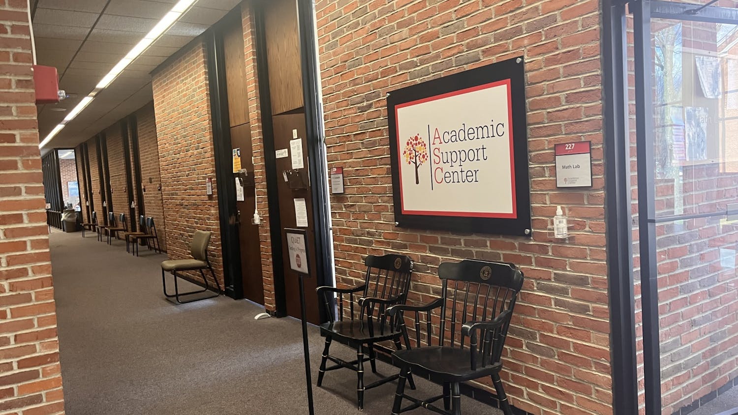 Brick walls surround a hallway with black chairs in them, and a sign that reads "Academic Support Center."