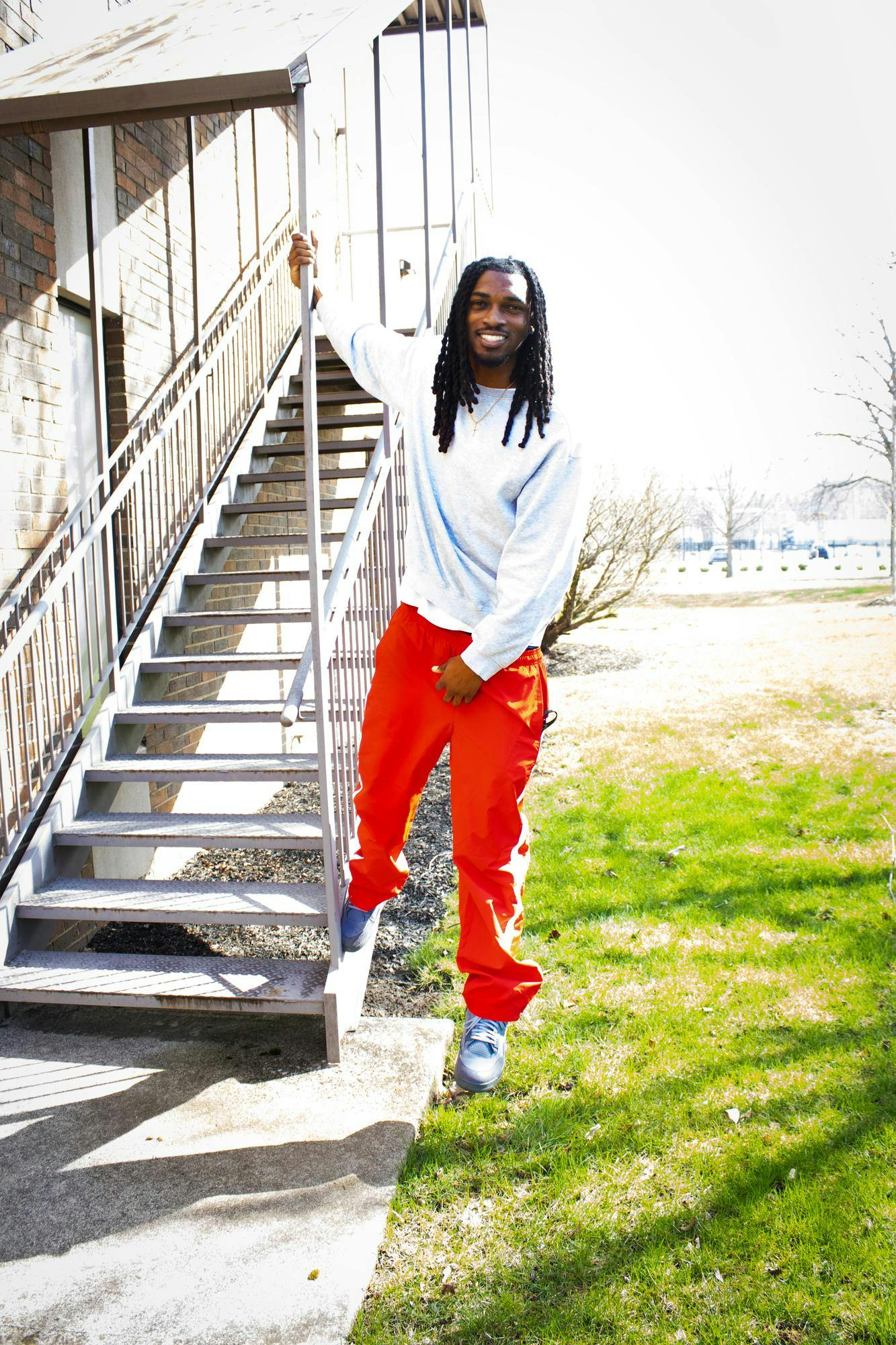 Editor-In-Chief MJ Davis leans away from a staircase while holding the railing. 