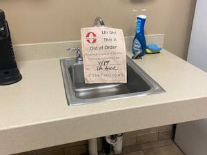 A sink in a dorm hall has an out-of-order sign attached to it. The sign reads "Uh Oh! This is Out of Order. A service request to fix this item was submitted on 9/19 by RA Aine. It'll be fixed soon!"