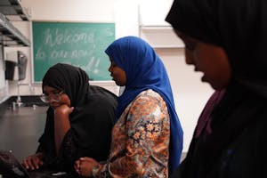 Three female students talk with one another and look at content on a computer in the new mosque.