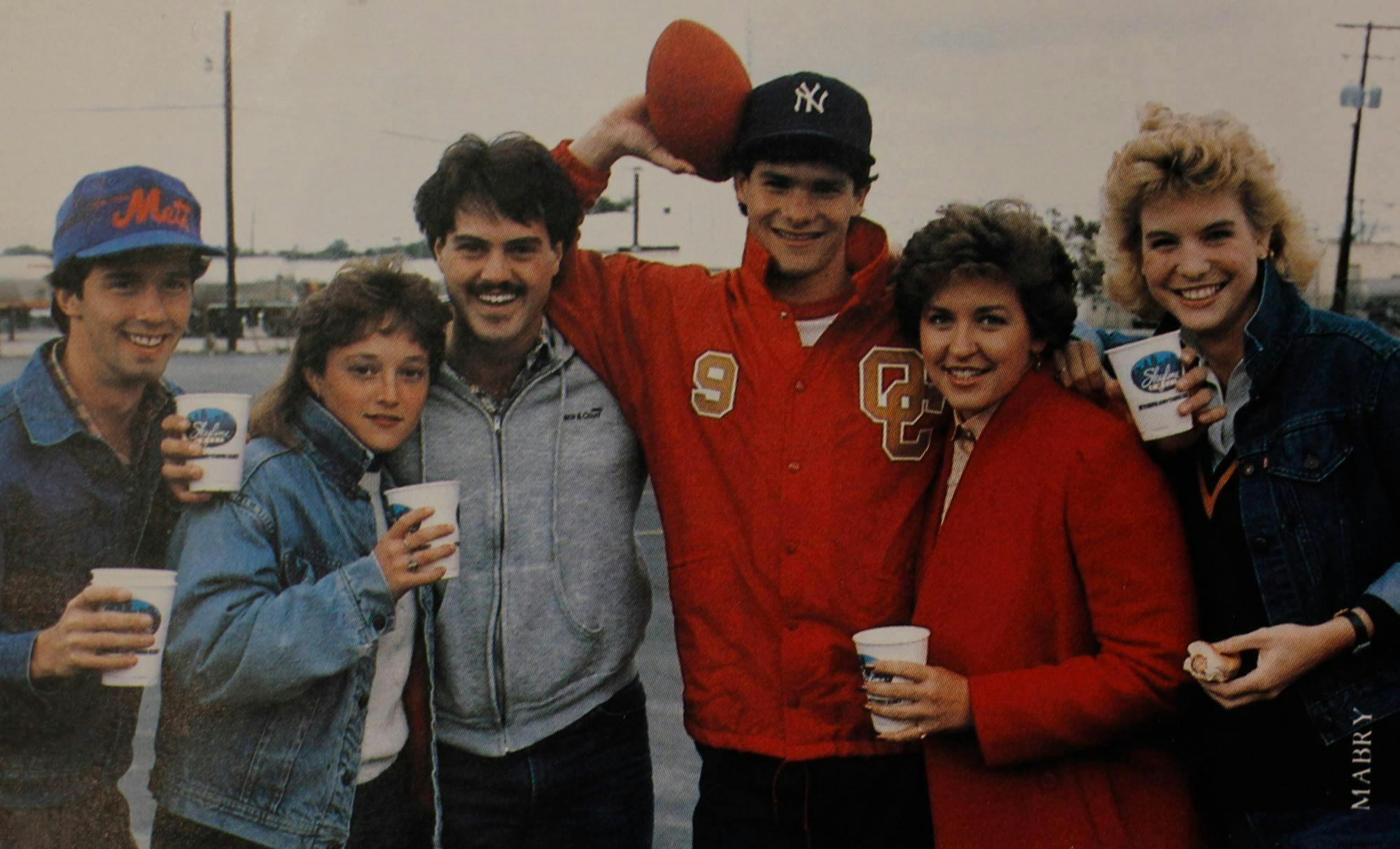 A photo of six people holding cups and smiling.