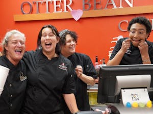 Four ladies with black uniforms laugh at one another making silly faces. 