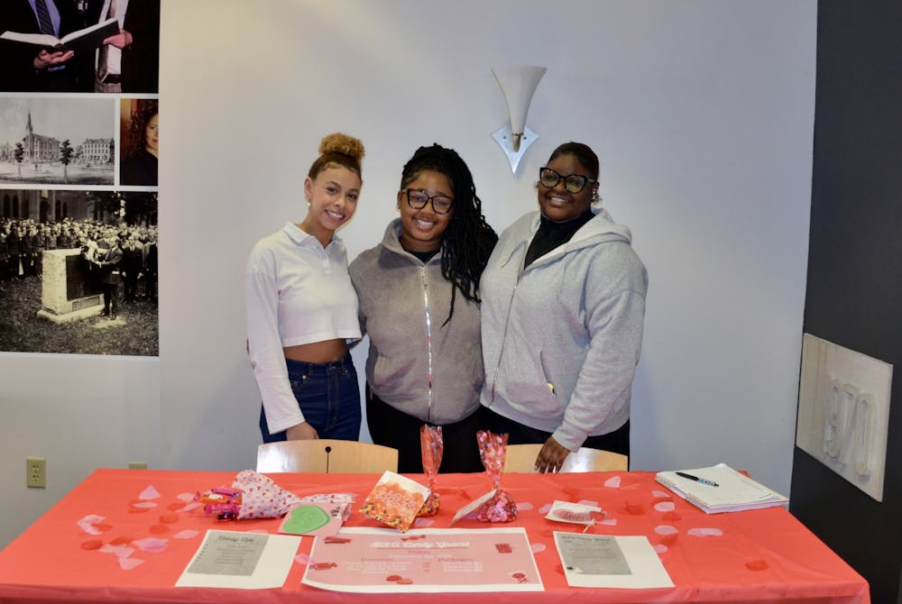 <p>Three members of the BSU selling candy-grams in the library.</p>