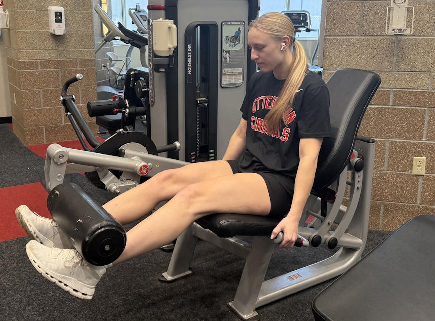 Girl with blonde hair doing seated leg extensions.