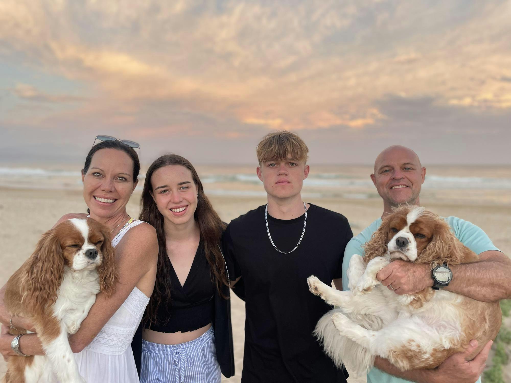 A family photo with dogs on a beach. 