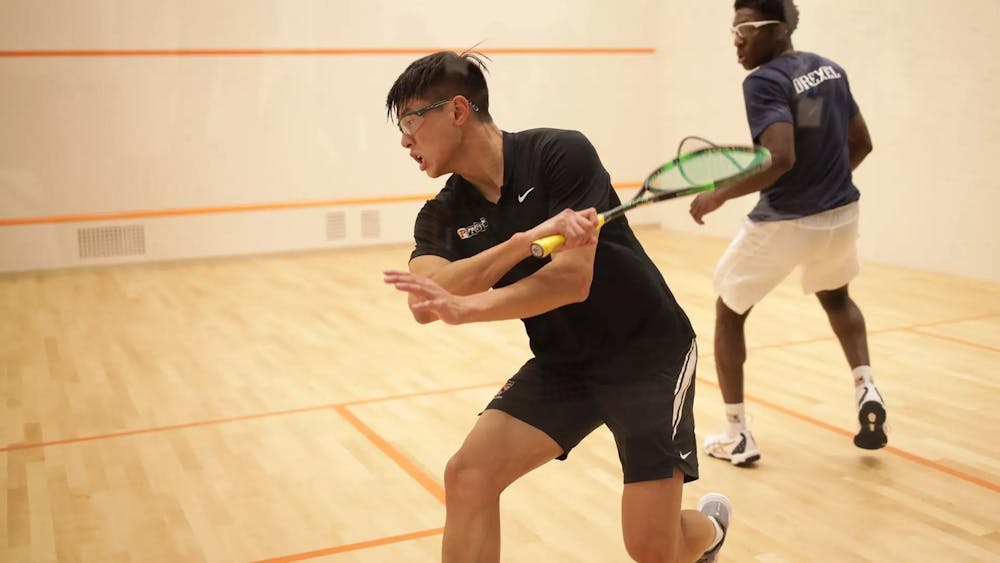 princeton squash player extends with racket, reaching to hit the ball 