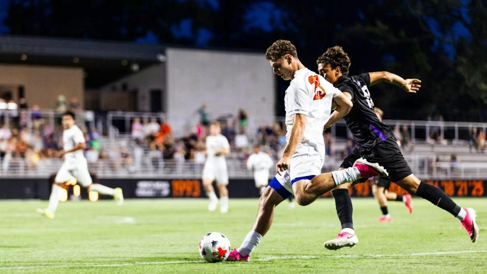 A player in a white and orange jersey kicks a soccer ball.